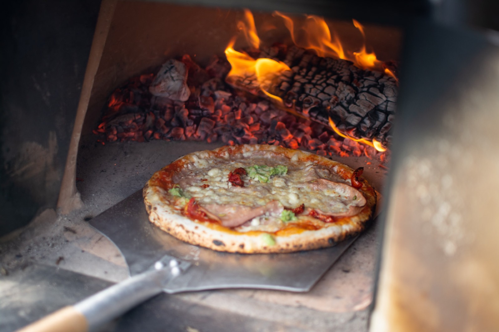 Pizza in de houtoven tussen de vlammen
