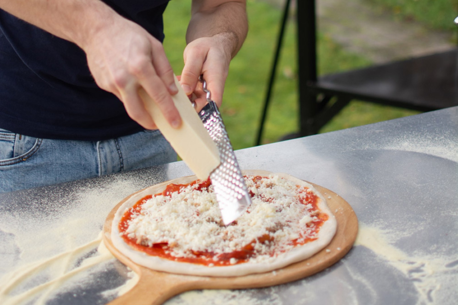 Kaas raspen over de pizza